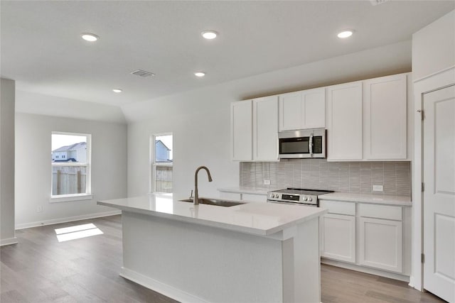 208 Seattle Slew Dr, Jarrell, TX 76537 - kitchen with stainless steel appliances, a sink, decorative backsplash, a center island with sink, and white cabinets