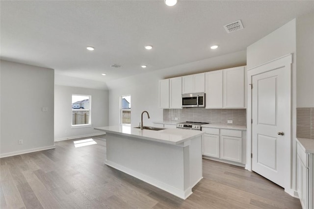 208 Seattle Slew Dr, Jarrell, TX 76537 - kitchen with stainless steel appliances, a sink, backsplash, a center island with sink, and white cabinets