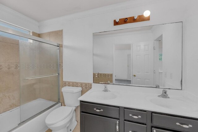 15009 Mossycup Ln, Austin, TX 78724 - full bath with double vanity, toilet, shower / bath combination with glass door, tile walls, and ornamental molding