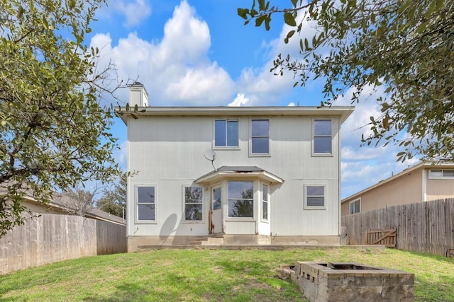 back of property with a yard, a fenced backyard, and a chimney