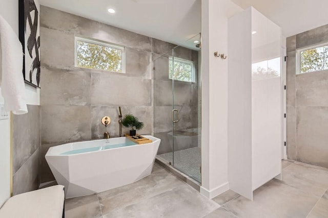 bathroom featuring recessed lighting, a freestanding tub, tile walls, and a shower stall