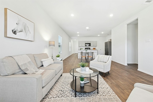 living room featuring baseboards, dark wood finished floors, visible vents, and recessed lighting