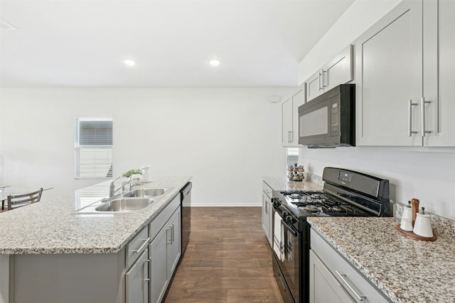 kitchen featuring dark wood finished floors, gray cabinets, a sink, black appliances, and baseboards