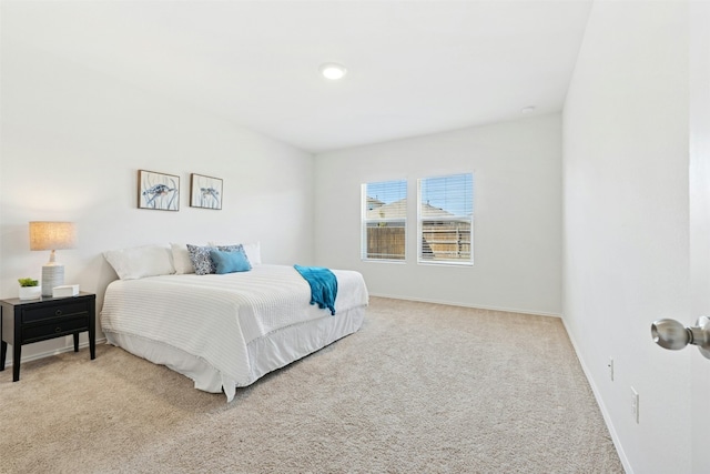 bedroom with light colored carpet and baseboards