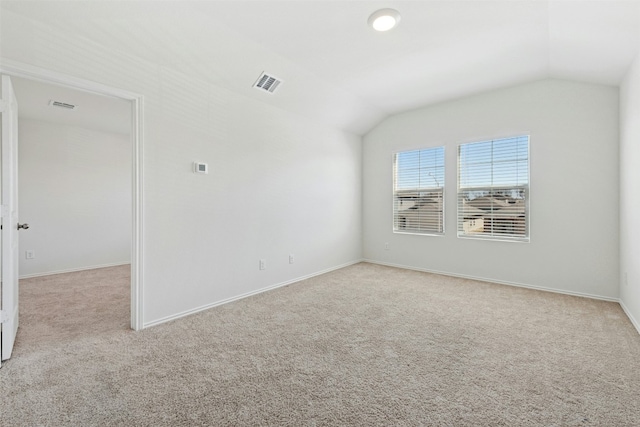 carpeted spare room featuring vaulted ceiling, visible vents, and baseboards