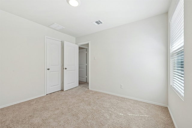 unfurnished bedroom featuring carpet floors, baseboards, multiple windows, and visible vents