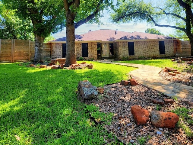 view of front facade featuring brick siding, fence, and a front lawn