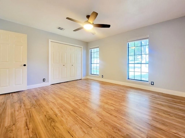 unfurnished bedroom with light wood-type flooring, baseboards, multiple windows, and visible vents