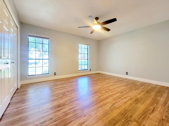 spare room with baseboards, plenty of natural light, and light wood finished floors