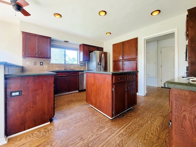 kitchen with appliances with stainless steel finishes, dark countertops, light wood-type flooring, and decorative backsplash