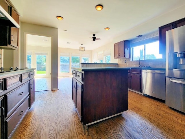 kitchen featuring plenty of natural light, appliances with stainless steel finishes, wood finished floors, and a center island