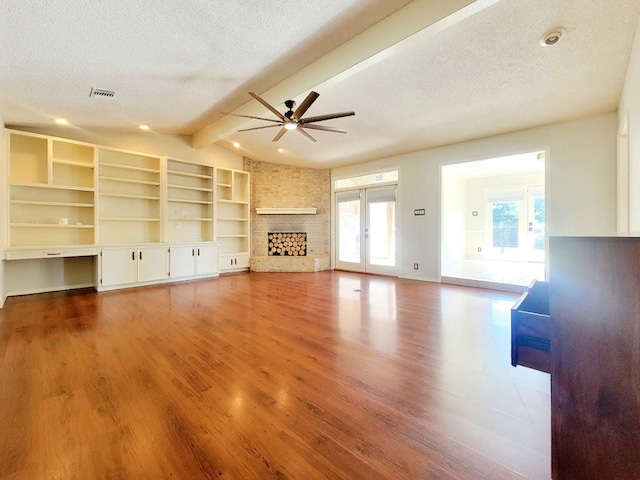 unfurnished living room with visible vents, a fireplace, a textured ceiling, and wood finished floors