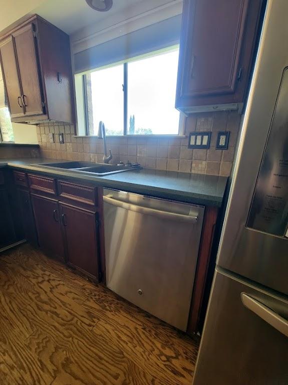 kitchen featuring appliances with stainless steel finishes, dark countertops, a sink, and tasteful backsplash