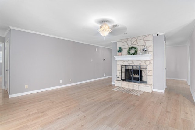 unfurnished living room featuring light wood-style floors, visible vents, crown molding, and a stone fireplace