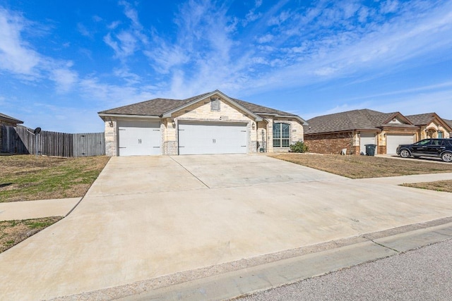 view of front of property with driveway, stone siding, an attached garage, and fence