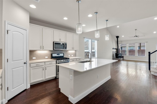 kitchen with stainless steel appliances, plenty of natural light, a wood stove, and a sink