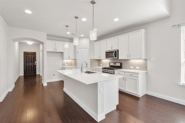 kitchen featuring tasteful backsplash, arched walkways, stainless steel appliances, and a sink