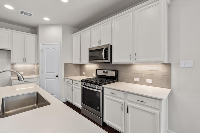 kitchen featuring visible vents, white cabinets, stainless steel appliances, light countertops, and a sink