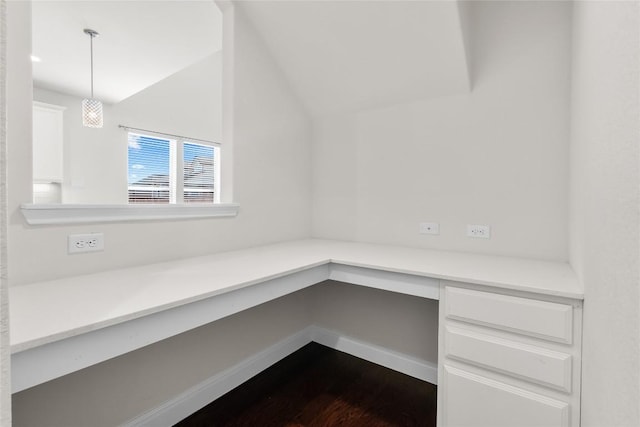 unfurnished office featuring lofted ceiling, dark wood-type flooring, built in study area, and baseboards