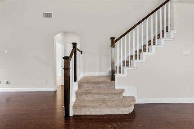 stairway featuring arched walkways, visible vents, baseboards, and hardwood / wood-style flooring