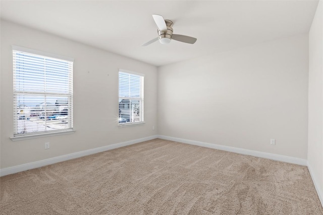 empty room featuring light colored carpet, ceiling fan, and baseboards