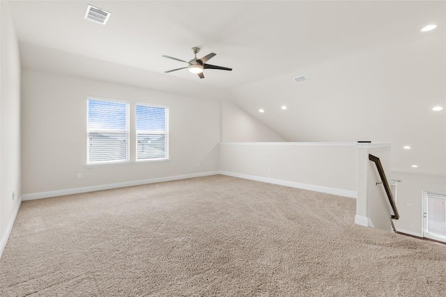 additional living space with light carpet, vaulted ceiling, visible vents, and baseboards