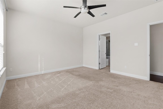 carpeted empty room with a ceiling fan, visible vents, and baseboards