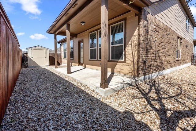 view of property exterior featuring an outbuilding, brick siding, a patio, a storage unit, and a fenced backyard