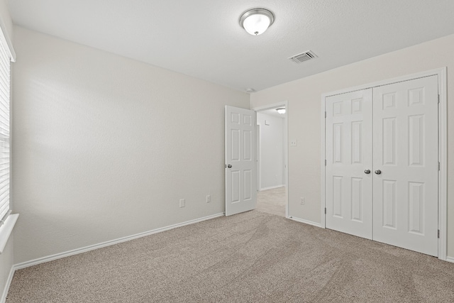 unfurnished bedroom with a closet, carpet flooring, visible vents, and baseboards