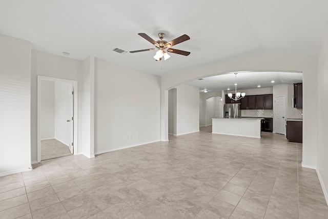 unfurnished living room featuring lofted ceiling, arched walkways, ceiling fan with notable chandelier, visible vents, and baseboards