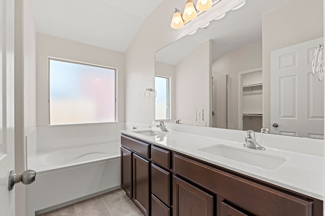 bathroom featuring lofted ceiling, a sink, a bath, and tile patterned floors