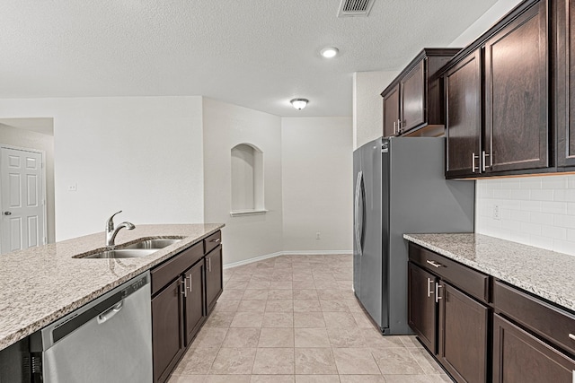 kitchen with light stone counters, stainless steel appliances, visible vents, backsplash, and a sink