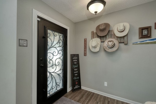 entryway with dark wood-style floors, baseboards, and a textured ceiling