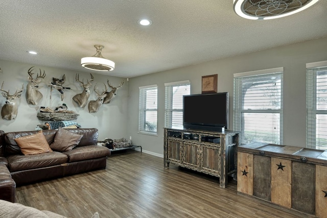 living room with dark wood-style floors, a textured ceiling, recessed lighting, and baseboards