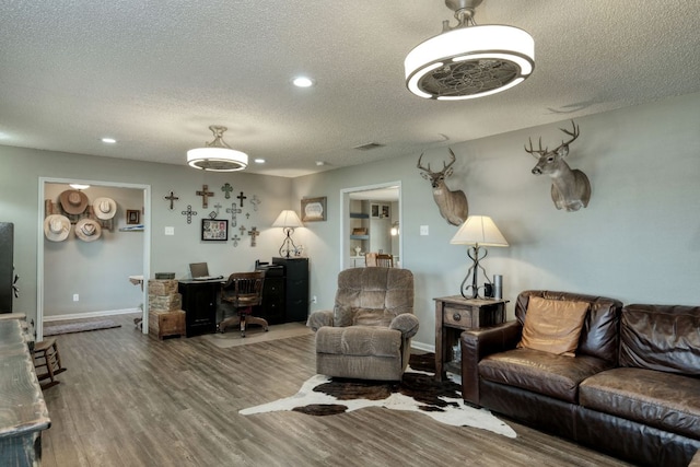 living room with a textured ceiling, recessed lighting, wood finished floors, and baseboards