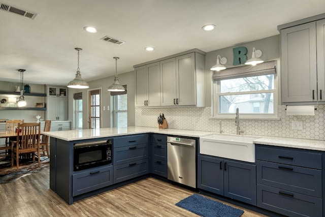 kitchen with visible vents, a sink, black microwave, dishwasher, and a peninsula