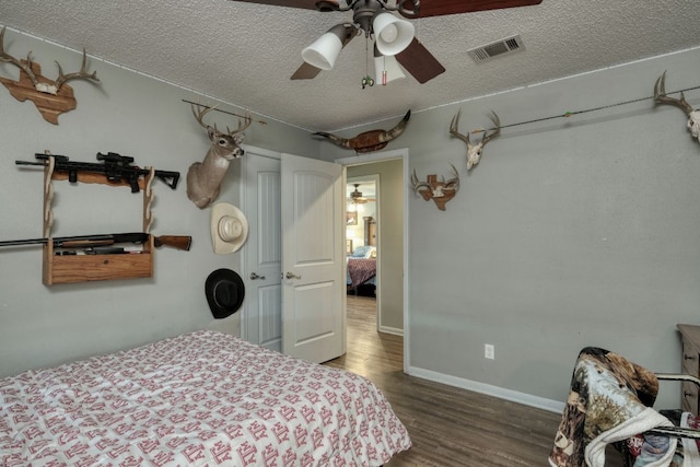 bedroom with baseboards, visible vents, a ceiling fan, wood finished floors, and a textured ceiling