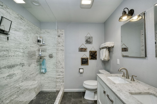 full bathroom featuring double vanity, toilet, a sink, a walk in shower, and baseboards