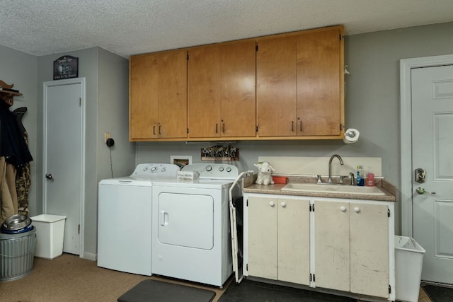 laundry area featuring cabinet space, a textured ceiling, a sink, and washing machine and clothes dryer