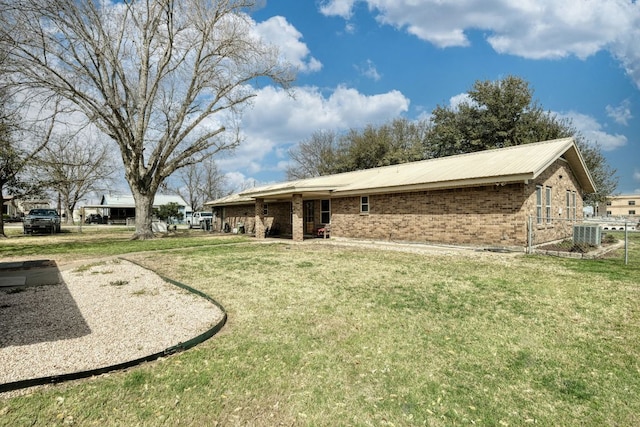 exterior space with brick siding, central air condition unit, a front yard, metal roof, and fence