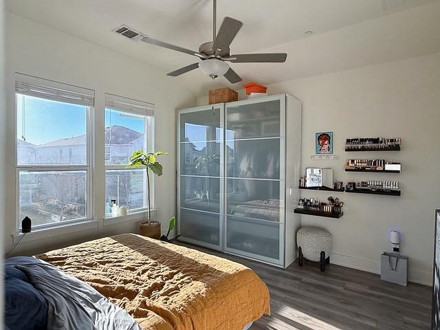 bedroom featuring a ceiling fan, wood finished floors, visible vents, and baseboards