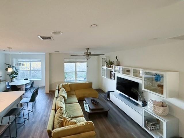 living area with baseboards, ceiling fan, visible vents, and wood finished floors