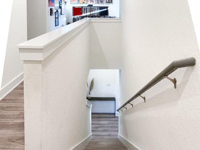 staircase featuring wood finished floors and baseboards