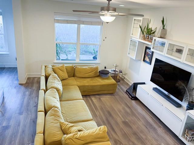 living area featuring a fireplace, wood finished floors, a ceiling fan, and baseboards