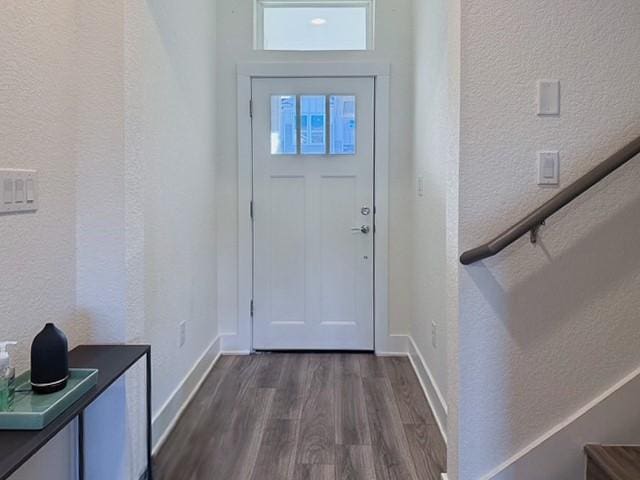 entryway with dark wood-style flooring, a textured wall, and baseboards