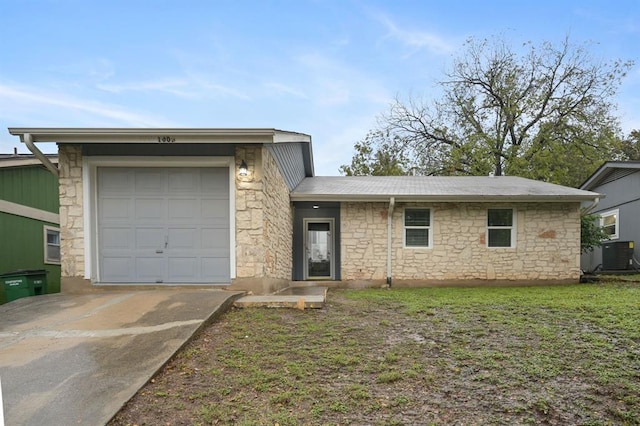 view of front facade with central air condition unit, a garage, concrete driveway, stone siding, and a front yard