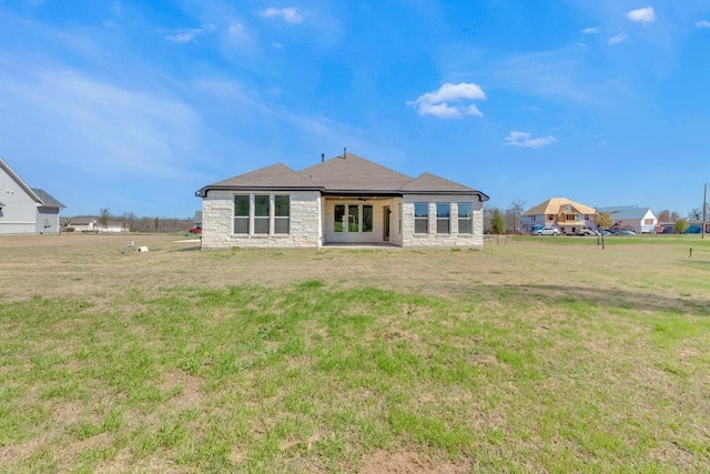 back of property with stone siding and a yard