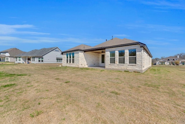 rear view of house featuring stone siding, a yard, and a patio area