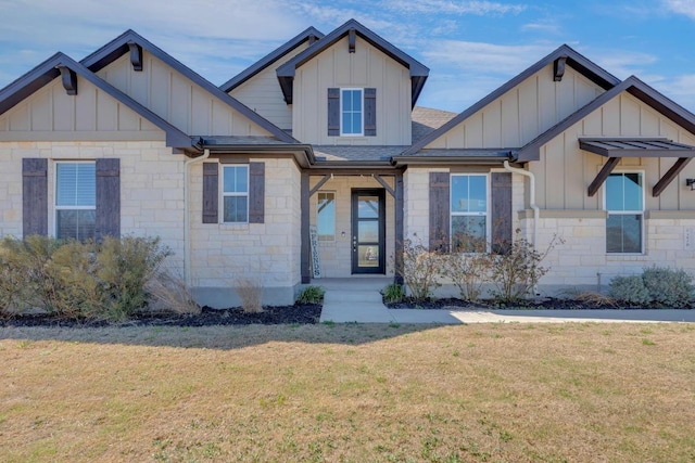 craftsman-style house featuring board and batten siding, a front yard, and stone siding