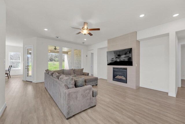 living room with light wood-style floors, a fireplace, baseboards, and recessed lighting